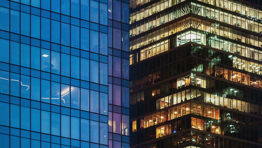 Day to night transition office windows lights time-lapse, modern high-rise skyscrapers, financial district tall glass buildings in downtown looking up wide angle shot, people working late evening
