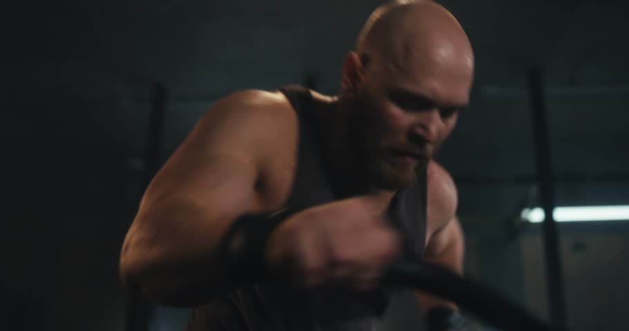 Close-up of an active male athlete making a quick movement while exercising on an exercise bike in the gym