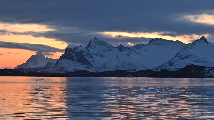 Sunset reflections over snowy mountains in a serene coastal landscape