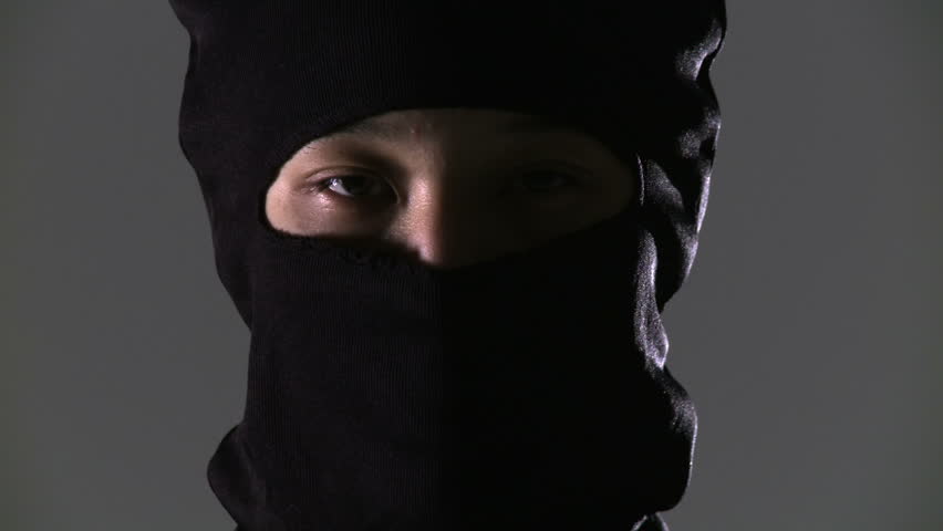 Masked ninja assassin rises up into the frame in a close up..
