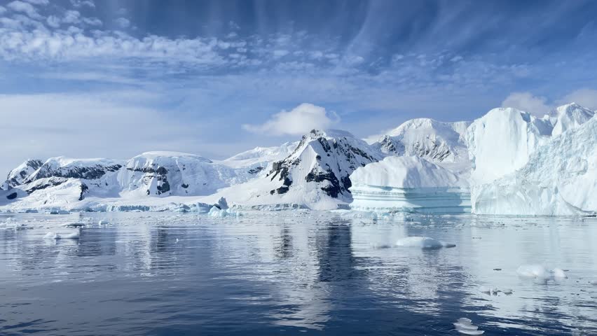 Majestic icebergs rise dramatically from deep blue waters on a cloudy day in Greenland