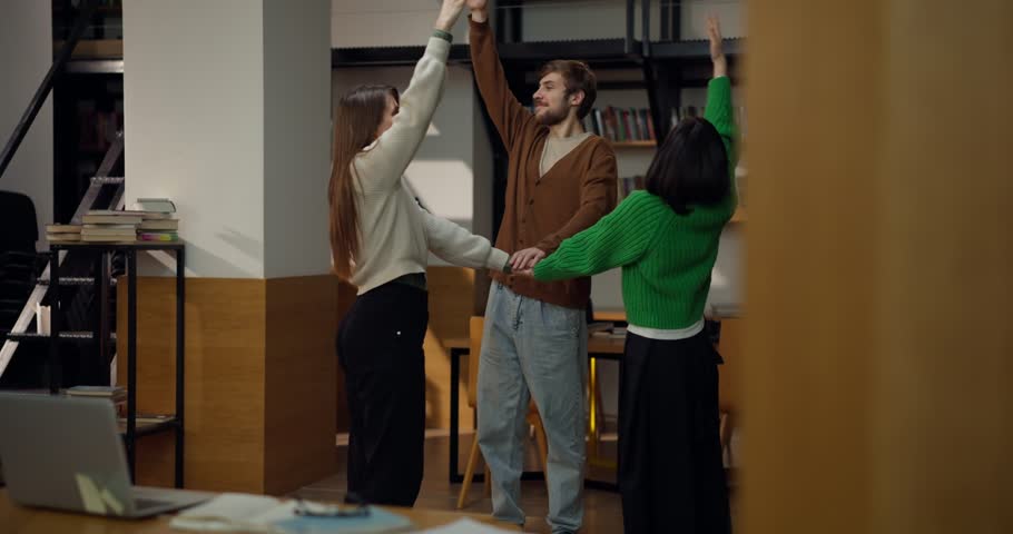 Trio of students practicing breathing techniques and teamwork exercises in library