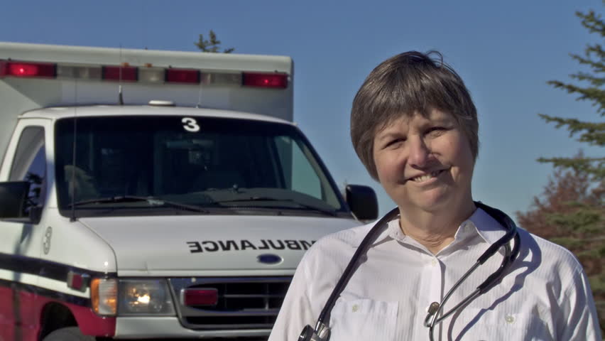 Paramedic standing in front of ambulance and wearing a stethoscope. Dolly from