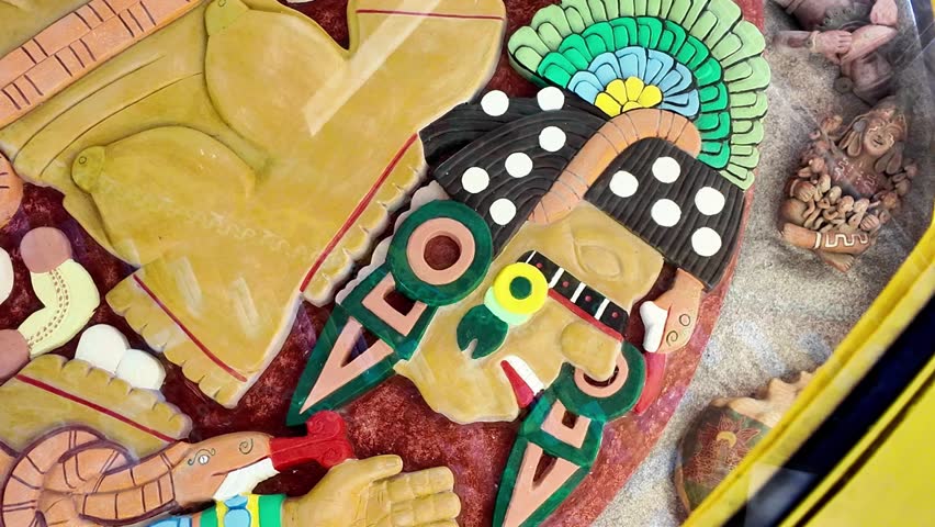 A man with a green headdress and a red and green face. The man is wearing a necklace