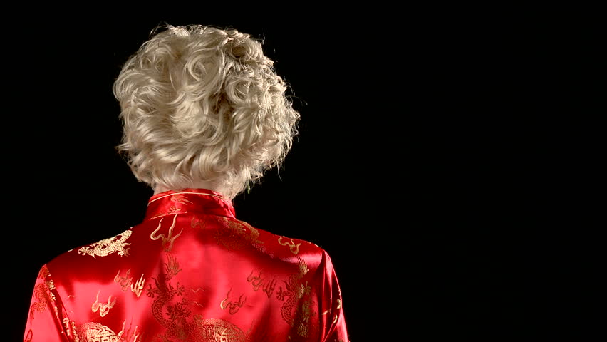 Attractive blonde in red cheongsam (Suzie Wong dress) turns to camera and