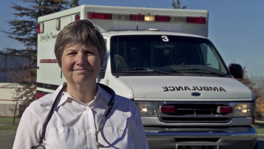 Paramedic standing in front of ambulance and wearing a stethoscope. Dolly from