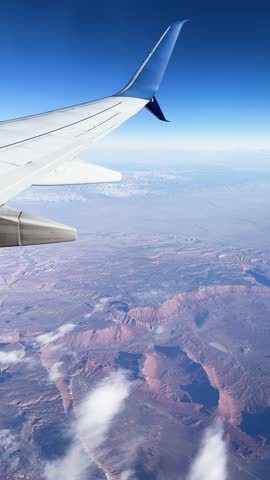 Aerial landscape captured from an airplane wing, showcasing mountains and clouds in a breathtaking view
