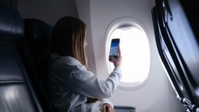 Woman enjoying an exciting flight, happily taking pictures through the airplane window - Powered by Shutterstock - Get 15% off with code: PIKWIZARD15