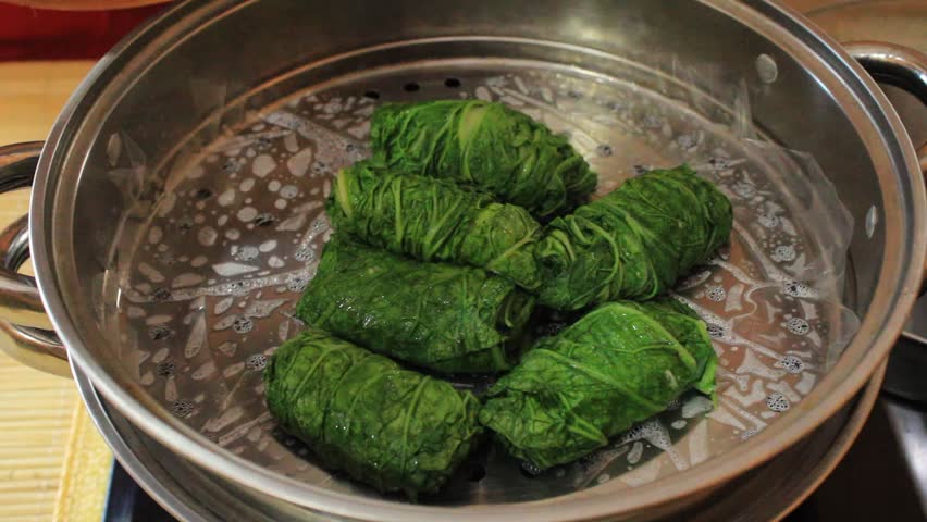 Rolled mustard greens that have been steamed. someone lifted the cooked rolled mustard greens