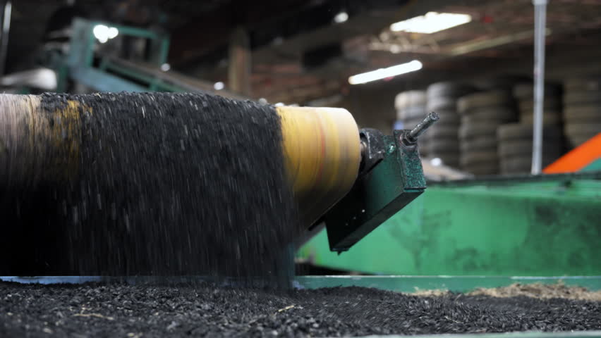 Recycling process of old tires. Industrial machinery shredding rubber into small granules for reuse.