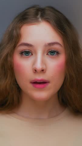 Portrait of Young Woman Eating Sweet Food as Looking at Camera. Real Person on Diet Consumes Chocolate Candy Bar as Lunch Snack. Playful Female Human Inside Cozy Living Room Alone with Sugary Fastfood