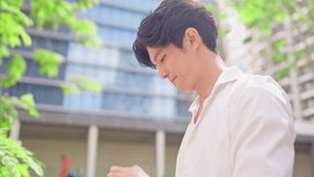 Asian young businessman chatting on smartphone while walking in city. Attractive handsome male employee worker communicate and discuss on mobile cellphone with colleagues outdoors with confidence. - Powered by Shutterstock - Get 15% off with code: PIKWIZARD15