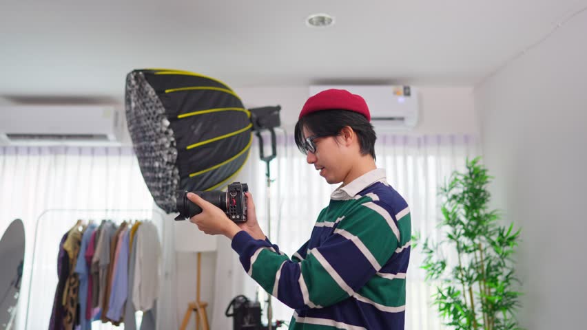 Asian cameraman shooting woman model with backdrop in photography studio. Attractive professional photographer taking beautiful pictures using techniques to create images for advertisement or movies.