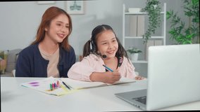 Asian loving mother support young kid daughter learning online in house. Happy family, attractive parent help and explain educate lesson subject to little child on laptop device in living room at home - Powered by Shutterstock - Get 15% off with code: PIKWIZARD15