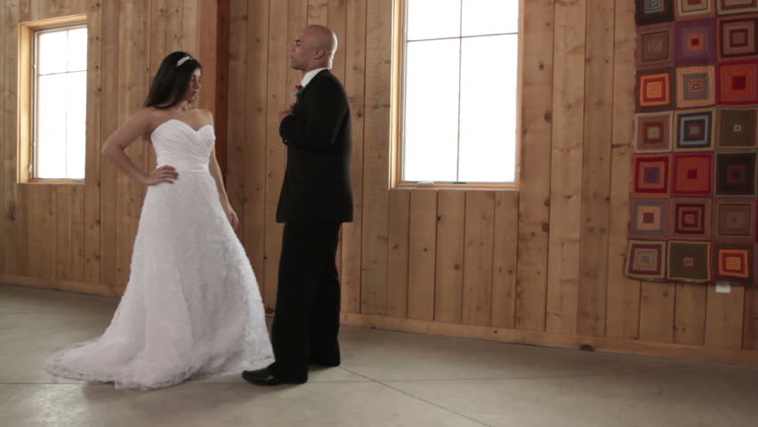Bride and groom in modern style wedding attire strike re-enact a proposal and