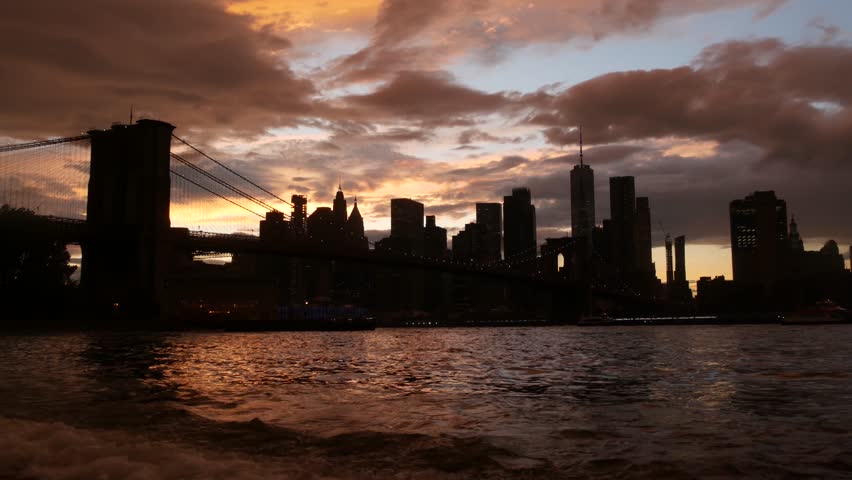Brooklyn Bridge, New York City Manhattan downtown skyline, financial district cityscape. United States World Trade Center skyscraper. Waterfront Pebble Beach, Dumbo, USA. Dramatic twilight cloudy sky.