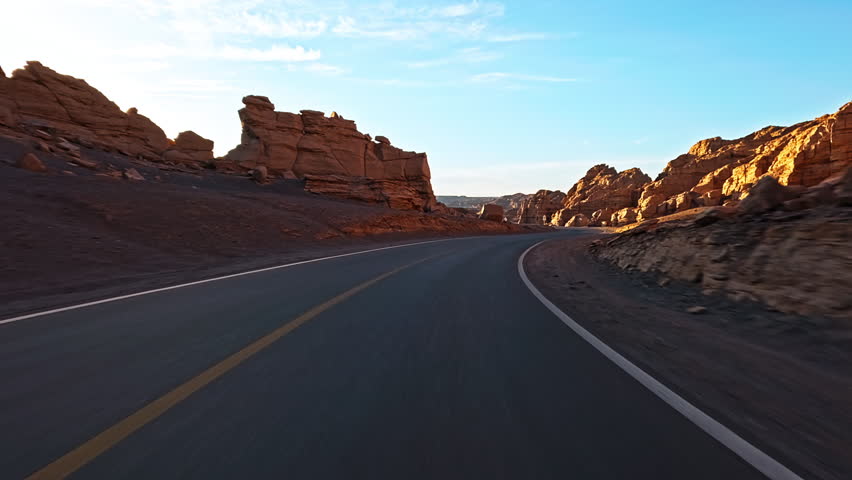 Driving a car through Yardang landform mountain in desert. Famous Dahaidao no man's land natural landscape in Xinjiang, China.