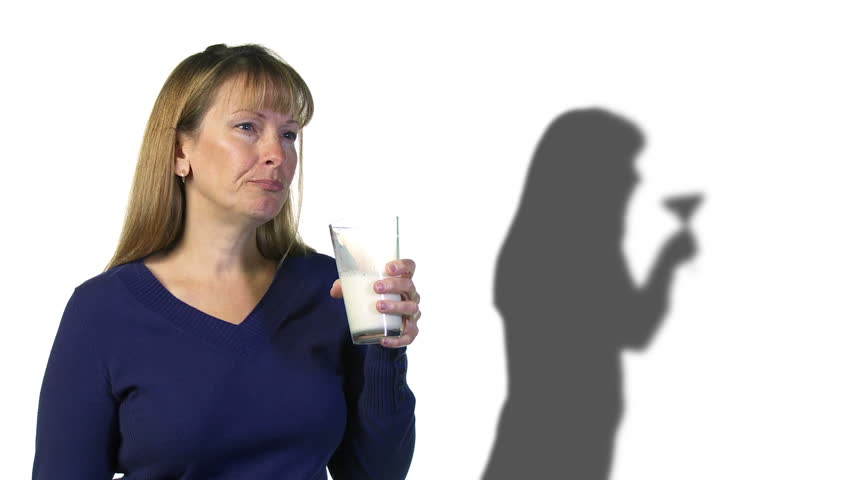 Woman drinks a glass of milk but her shadow drinks a martini.