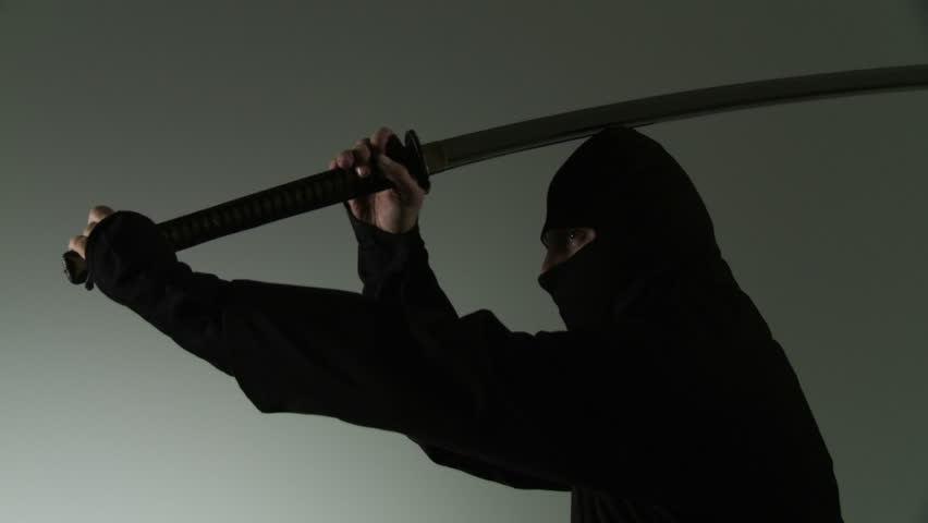 Medium close up of a masked ninja swinging a two-handed Japanese sword, pausing