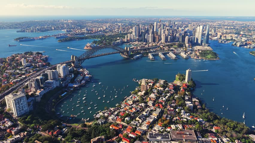 Drone video from above north Sydney facing the CBD with lavender bay, the opera house and harbour bridge. Drone flies slowly toward the west revealing more of surrounding harbour and suburbs