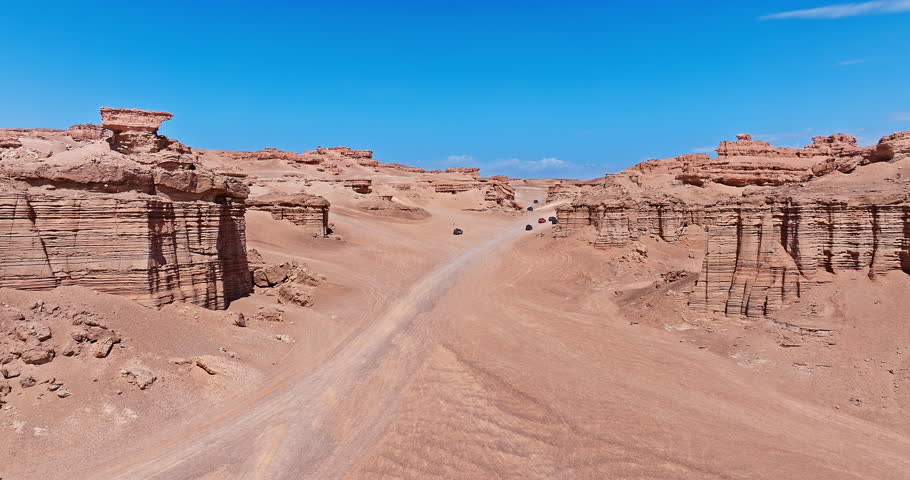 Cars driving on dirt road through a vast canyon. Famous Dahaidao no man's land natural landscape in Xinjiang, China.