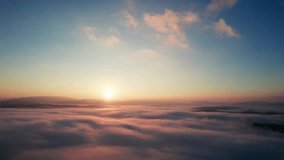 Aerial view of sun rises above sea of clouds, painting sky with soft hues of orange and blue. Light, wispy clouds scatter across horizon, capturing serene and beauty of dawn breaking over landscape. - Powered by Shutterstock - Get 15% off with code: PIKWIZARD15