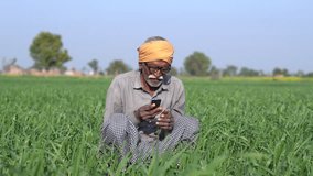 Senior rural indian farmer sitting outdoor at agriculture filed talking on mobile phone. Elderly man using cell phone, Wireless technology. People on india. - Powered by Shutterstock - Get 15% off with code: PIKWIZARD15
