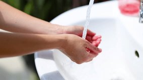 Hands being washed under running water in an outdoor sink. Bright lighting highlights cleanliness and hygiene in a tropical setting - Powered by Shutterstock - Get 15% off with code: PIKWIZARD15
