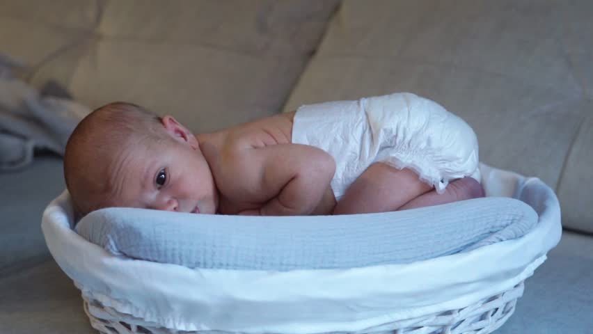 Newborn baby lying in basket wearing diaper