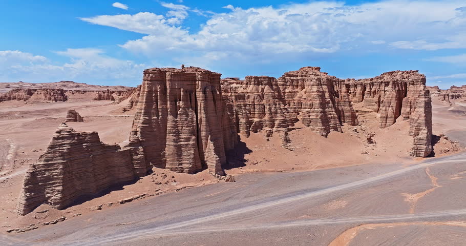 Spectacular eroded sandstone cliffs tower over a vast desert canyon under blue sky. Famous Dahaidao no man