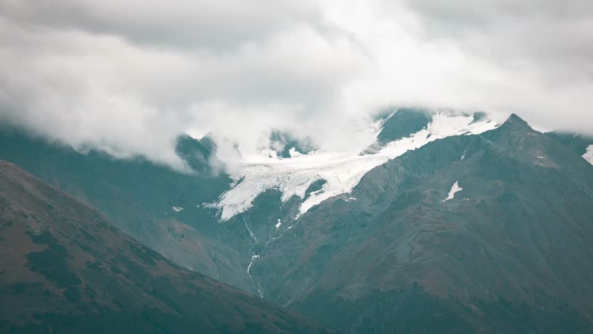 Glacier and rocky mountains of Alaska with flowing clouds, time lapse view