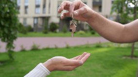 Man handing house keys with a house-shaped keychain to a woman, outdoors, real estate concept. - Powered by Shutterstock - Get 15% off with code: PIKWIZARD15