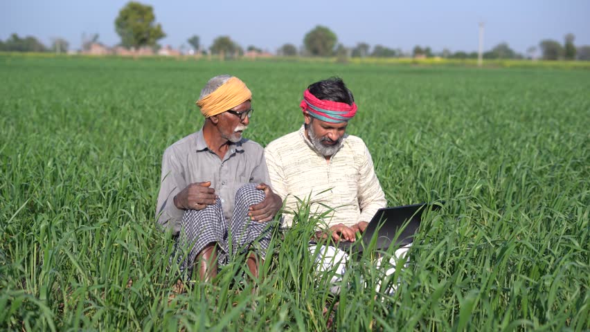 Happy Rural indian farmers sitting at agriculture field using laptop.to thumbs up, People of india learning computer. Wireless technology. Son show government scheme to his father.