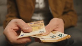 Close-up of man counting euro banknotes at home. Person planning his personal finances, sitting on sofa with cash money. Concept of planning home budget, savings and personal finances - Powered by Shutterstock - Get 15% off with code: PIKWIZARD15