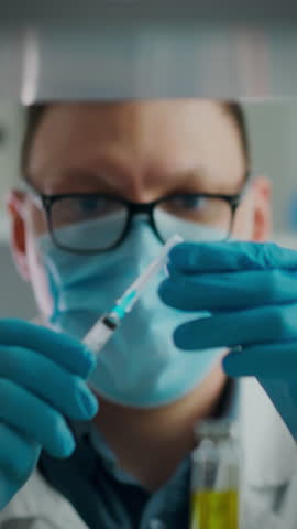 In a clinical environment, the anesthesiologist, wearing a mask and gloves, meticulously draws medication from a vial into a syringe, ensuring precision and safety for the upcoming procedure