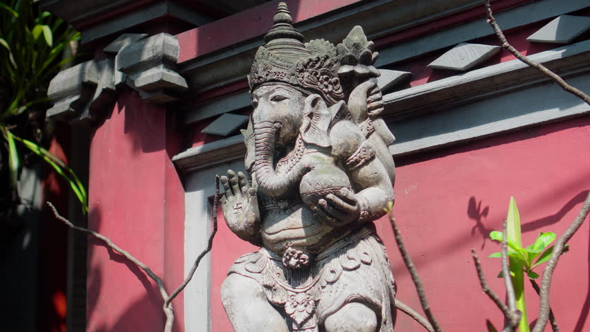 An old hindu stone statue of Ganesha covered with moss, standing on the street on the Bali island in indonesia