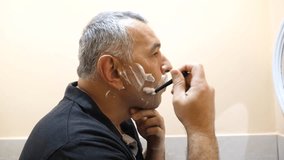 A man uses shaving foam and shaves with a manual razor in the bathroom. - Powered by Shutterstock - Get 15% off with code: PIKWIZARD15