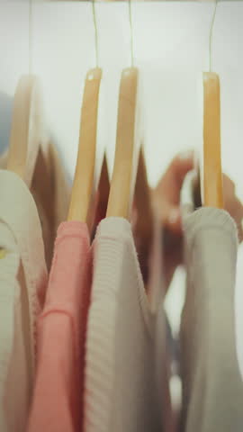 A modern fashion enthusiast curates her wardrobe, carefully choosing clothes that reflect her style. This activity takes place indoors, showcasing her dedication to fashion and self-expression