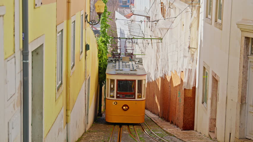Lisbon, Portugal, 26 February 2025: The old yellow tram, funicular on the narrow street in Lisbon