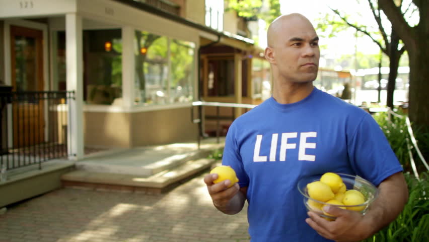 Man takes lemons from a guy in a blue T-shirt that says 
