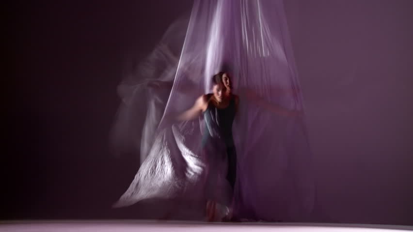 Gymnastic young woman dances with silks, runs towards camera. Composited with