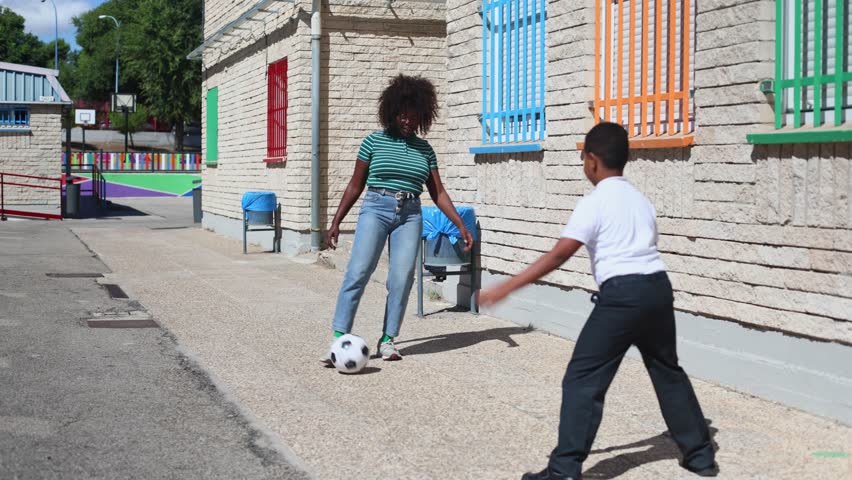 Young students engaging in soccer game, boy and girl kicking ball with enthusiasm while playing together in vibrant schoolyard during sunny day