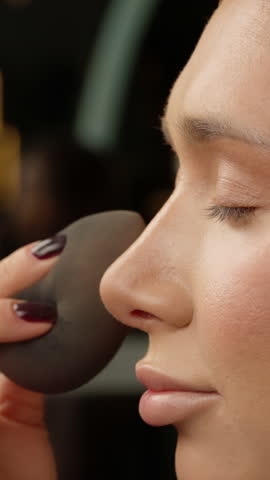 Professional makeup artist blending foundation onto model