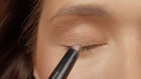 Professional makeup artist applying shimmering eyeshadow on model's eyelid with precision brush, capturing delicate beauty technique in professional studio lighting - Powered by Shutterstock - Get 15% off with code: PIKWIZARD15
