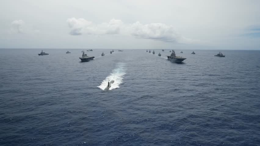 Multinational Navy Aircraft Carrier Ships and a Submarine Steam in Formation During a Group Sail off the coast of Hawaii during Exercise Rim of the Pacific.