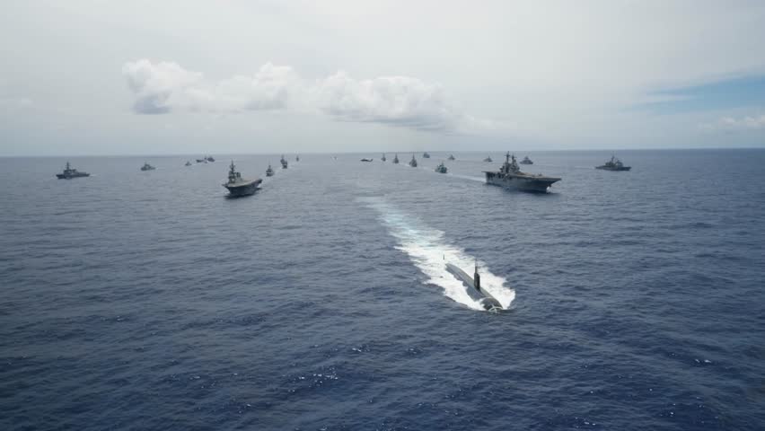 Multinational Navy Aircraft Carrier Ships and a Submarine Steam in Formation During a Group Sail off the coast of Hawaii during Exercise Rim of the Pacific.