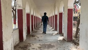 Shot of male walking through haunted corridor with series of arched openings of a building. - Powered by Shutterstock - Get 15% off with code: PIKWIZARD15
