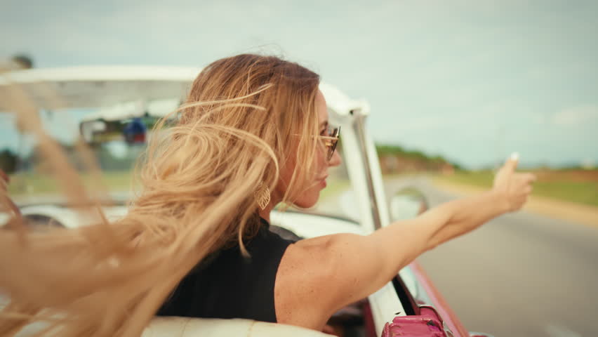 Portrait of beautiful woman on passenger seat in white cabriolet in summer. Happy lady with sunglasses for eyes protection, pretty rich female person enjoying auto trip on luxury car in summertime