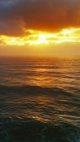 Aerial view on big waves of Atlantic ocean and dramatic sunset sky. Vertical video