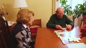 Elderly couple playing dominoes on a wooden table in their living room, enjoying their free time together - Powered by Shutterstock - Get 15% off with code: PIKWIZARD15